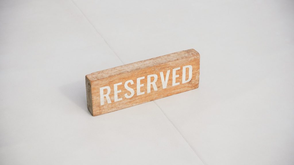 Panneau en bois « Reserved » posé sur une table : réduire les no-show au restaurant